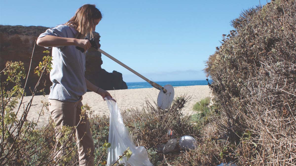 Volunteer Abby Herring fills up a garbage bag with trash left over from beachgoers at Panther Beach