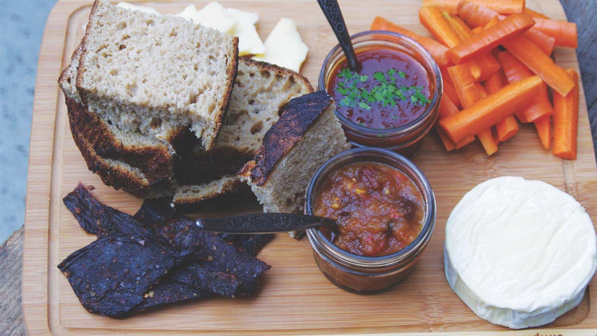 Local preserves on a cutting board with pickles and bread