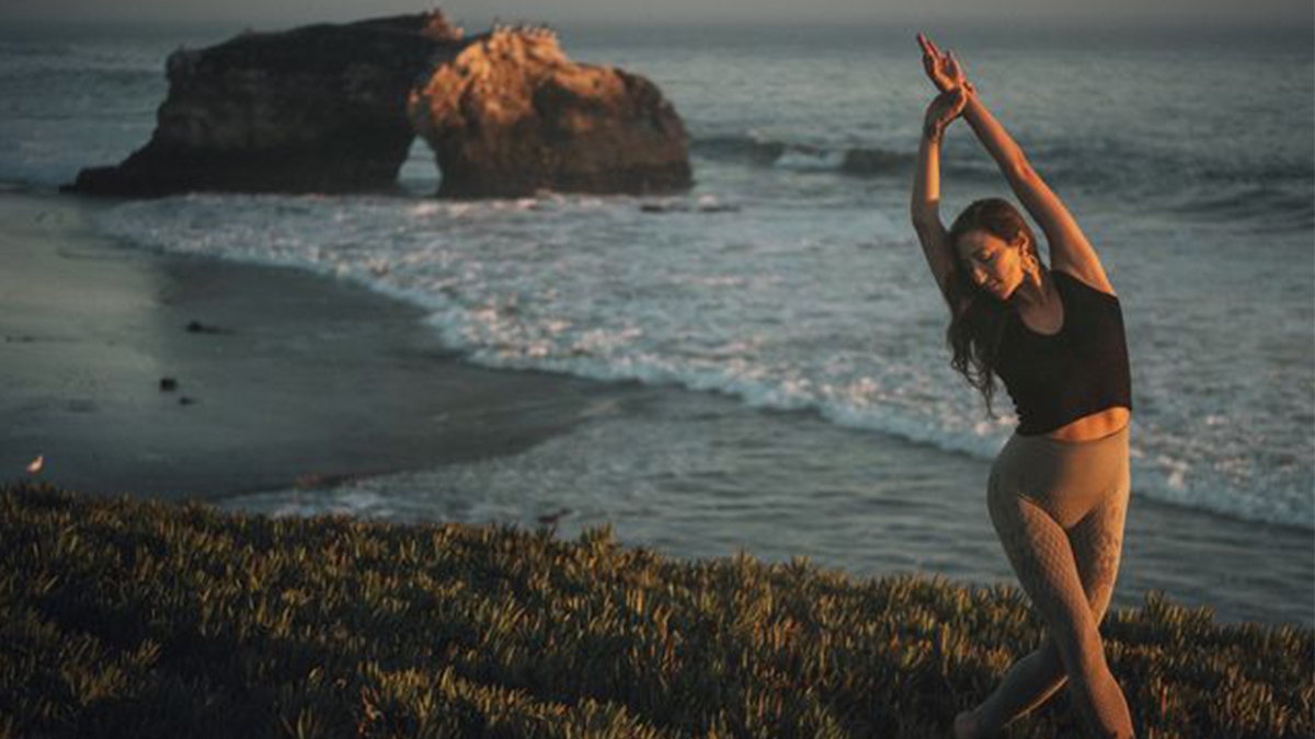 Divinitree Yoga teacher Magnolia Rasa stretches at Natural bridges State Beach.