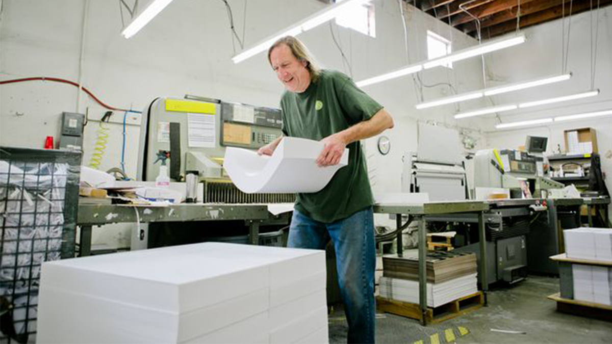 Clint Bower moves a heavy stack of papers during a busy day of work at the cooperatively owned Community Printers.