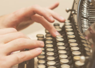 fingers typing on a vintage typewriter