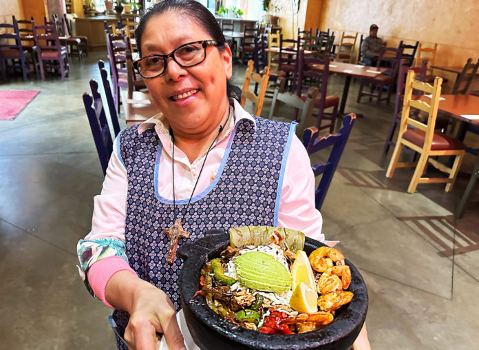Watsonville’s El Alteño: Family Style, 20 Years Woman holding a dish served in a round stone dish known as a molcajete