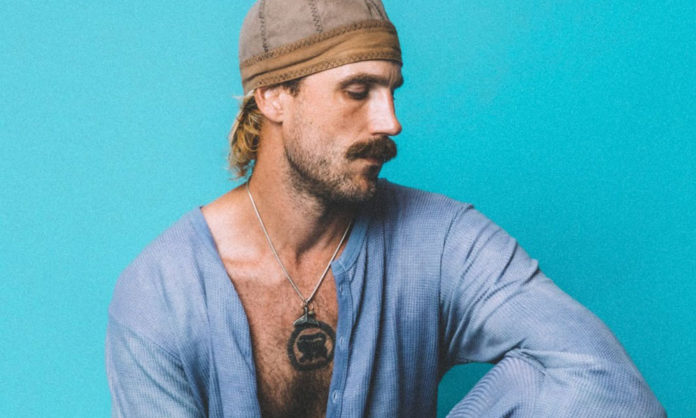 Rayland Baxter Flys into Rio Theatre for May 14 Concert Portrait of a man on a bright blue background