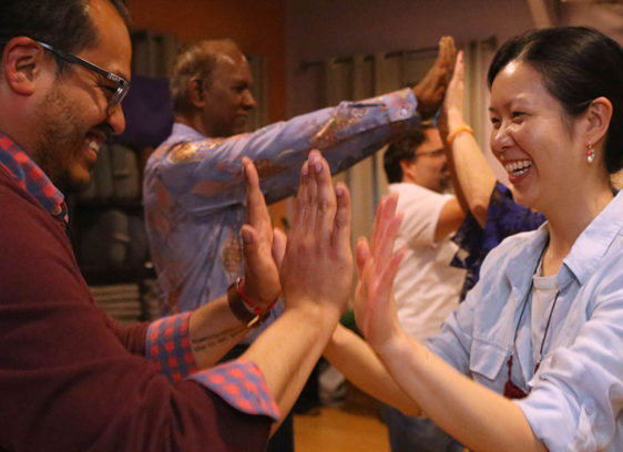 Tantra Speed Dating: Where Mindful Singles Meet and Mingle People in a group raising their hands to touch others