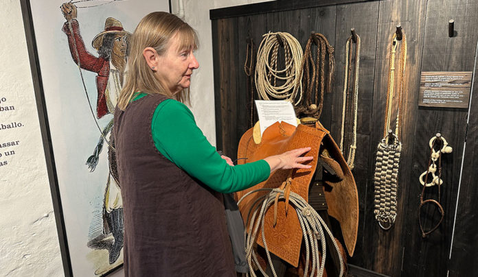 Door to the Past Now Open at Restored Castro Adobe Woman in front of a wall display of historical artifacts