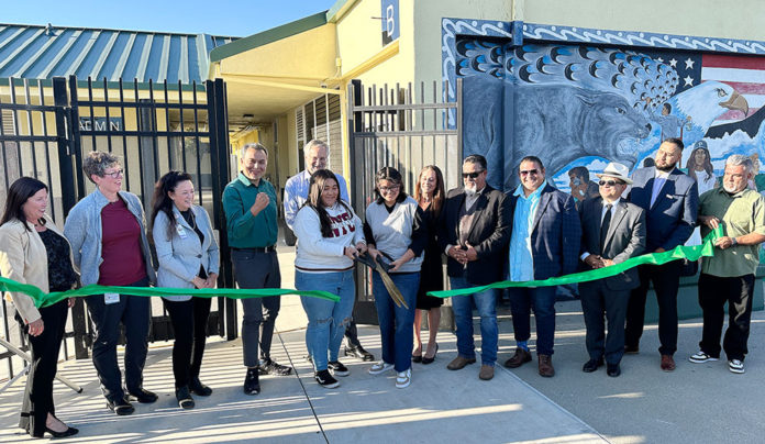 Pajaro Middle School Reopens After Devastating Flood Row of people in front of a long ribbon with a person cutting it