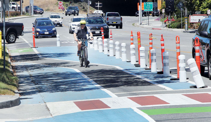 Locals Applaud Capitola Crosswalk Street with various zones of the pavement painted different colors (blue, green, and white-and-red stripes)