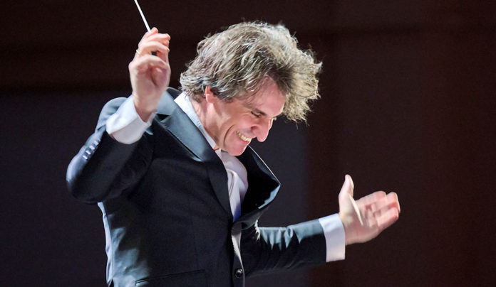 Music, Maestro! Man vigorously waving a baton like a conductor