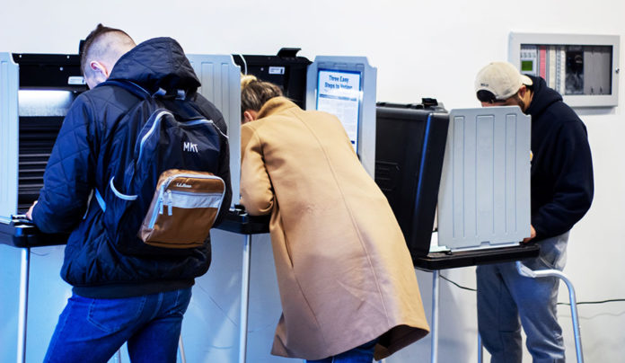 Where to Vote in Santa Cruz County Three people in a row of voting booths