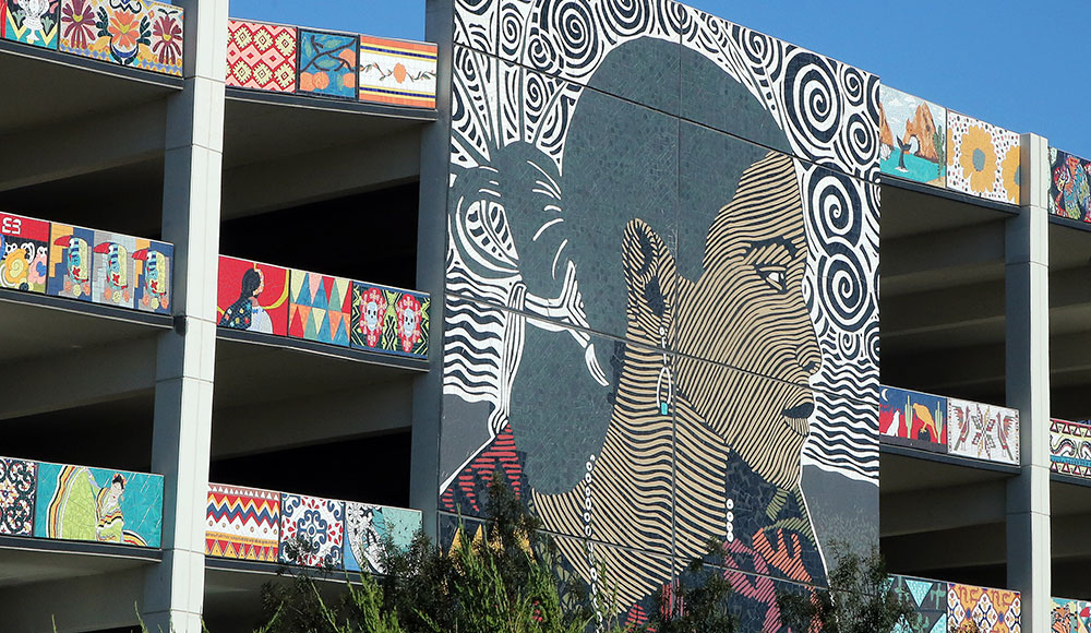 Exterior of a parking garage decorated with colorful mosaic artwork