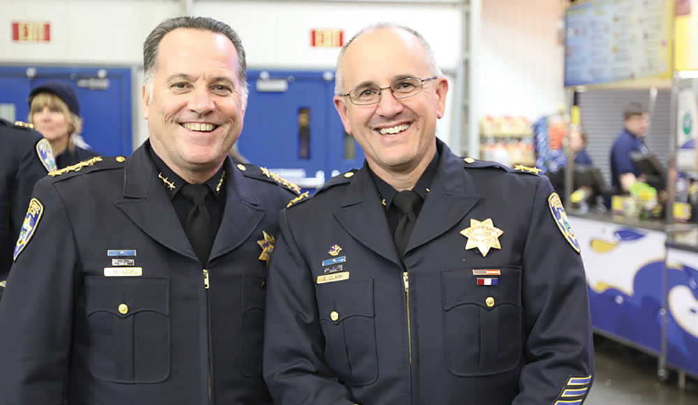 Two men in police uniforms smiling at the camera