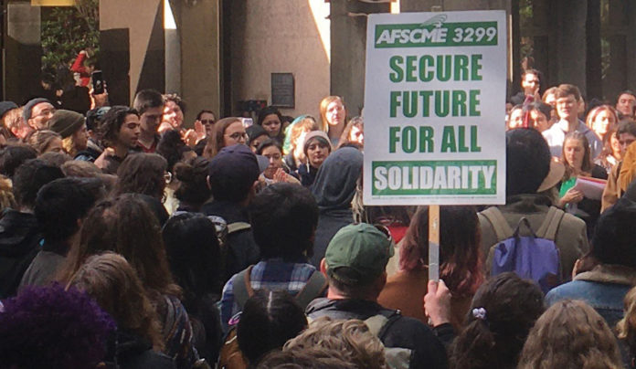 Workers in the UC System Remain Without a New Contract Crowd of protestors with a union sign reading "Secure Future for All"