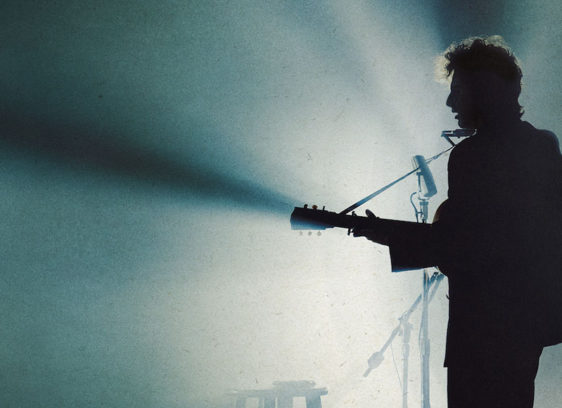 Visions of Dylan Man playing the guitar on stage, in silhouette