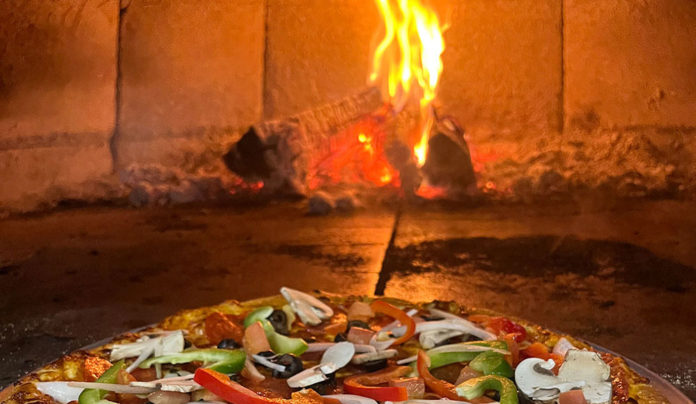 Pie Chart Pizza in front of the opening into a wood-fired stove
