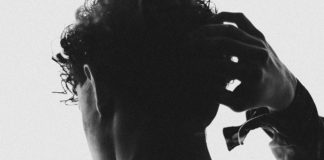 Man photographed from behind in silhouette, putting his hand on his head
