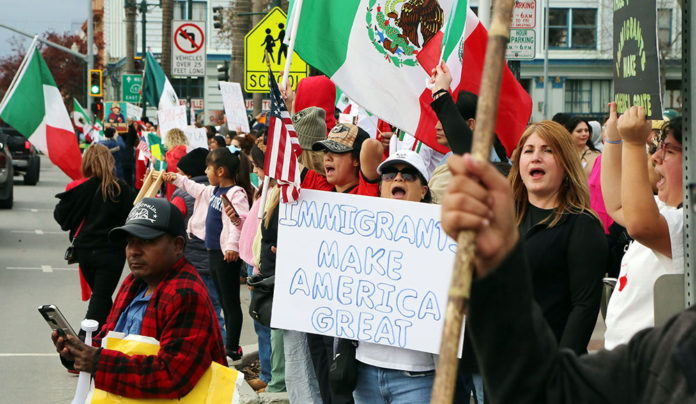 Laborless Day Group of people holding up signs and Mexican flags on the street
