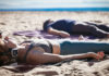Two people lying on towels in the sand