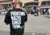 Man at a rally wearing a shirt that says “Fighting Nazis Since 1996”