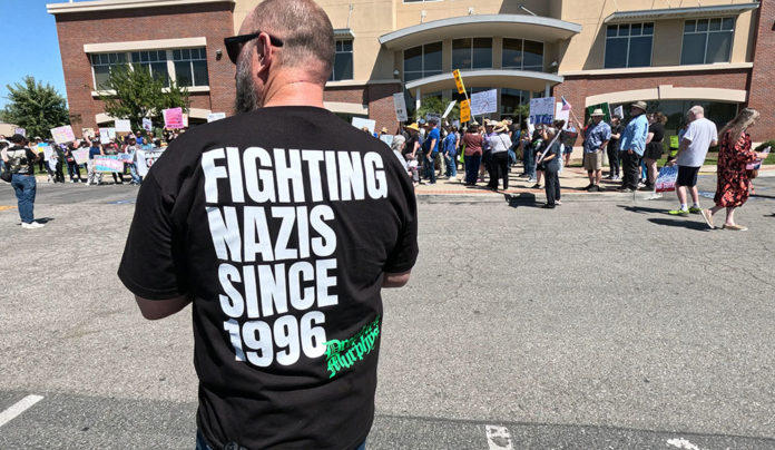 Collective Action Man at a rally wearing a shirt that says “Fighting Nazis Since 1996”