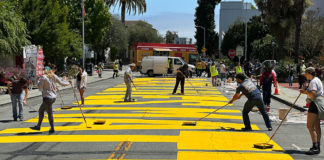 People applying paint to giant letters on a city street