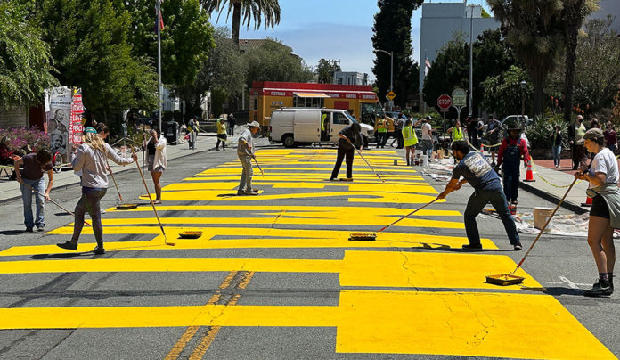 Community Unites to Repaint Black Lives Matter Mural People applying paint to giant letters on a city street