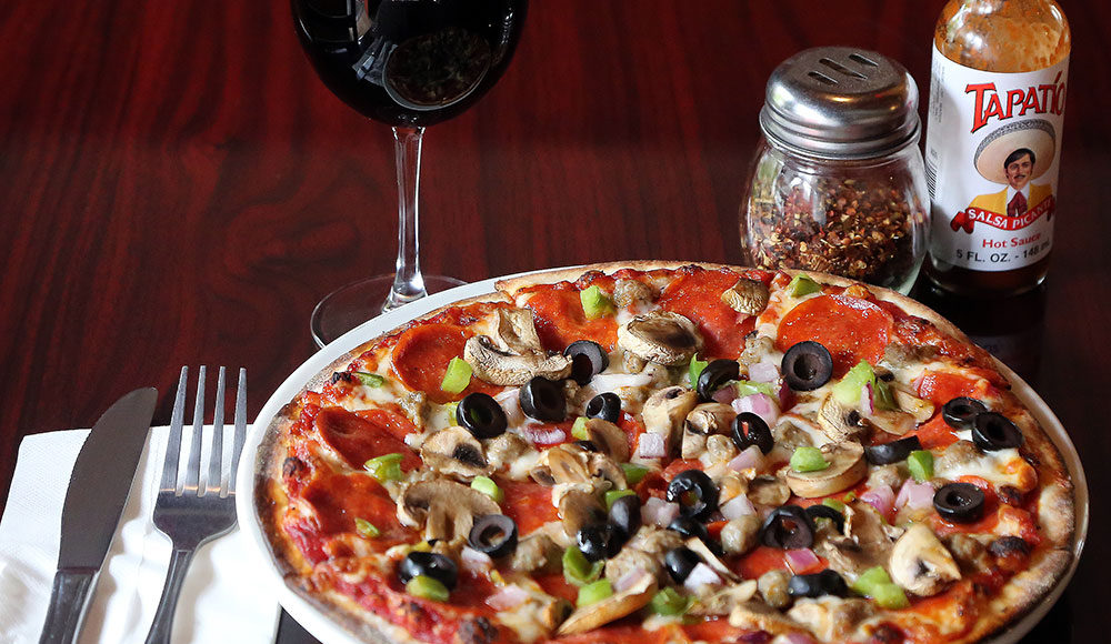 Foodie File photo. A combination pizza and a glass of red wine at Mangiamo Pizza