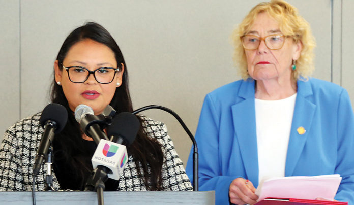 H.R. 4696 Would Provide Path to Citizenship Woman speaking into a microphone standing next to another woman holding a document