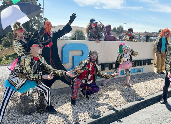 ‘Clowns’ Stage Theatrical Protest at Bomb Component Facility Several people in clown costumes congregate around the main entrance of a company