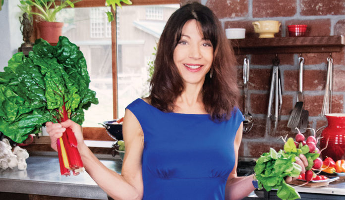 Santa Cruz Wellness Expo Offers Demos for Health-Minded People Woman in a kitchen holding up fresh produce