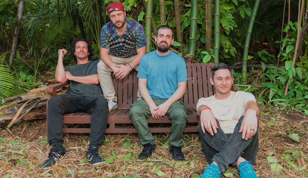 the band Spafford seated on a bench in a bamboo grove.