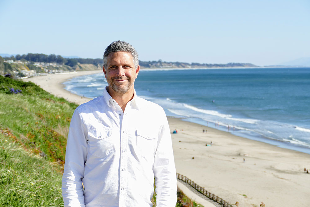 Man standing on a cliff with the ocean behind him