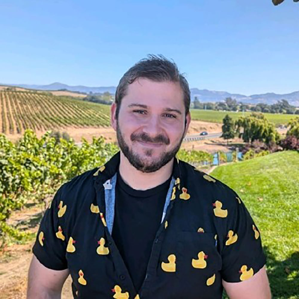 Photo of a man in front of a landscape with a vineyard