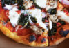 Amore Foray La Posta’s salsiccia pizza, adorned with tomato, kale, burrata and house-made sausage.