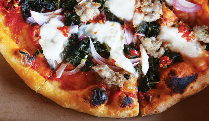 Amore Foray La Postaโs salsiccia pizza, adorned with tomato, kale, burrata and house-made sausage.