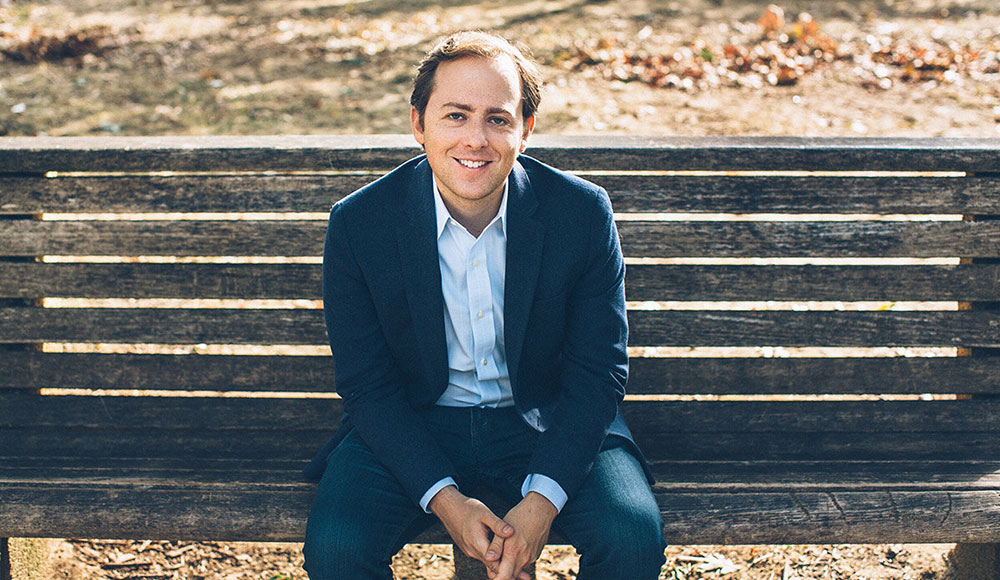 David Litt seated in a casual blue suit