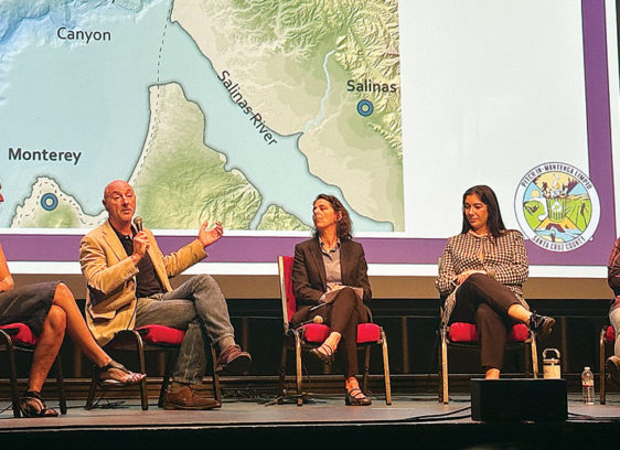 An ocean view, pollution included Panel of five speakers discussing ocean pollution at the Rio Theatre in Santa Cruz, seated before a map of Monterey Bay and the Salinas River.