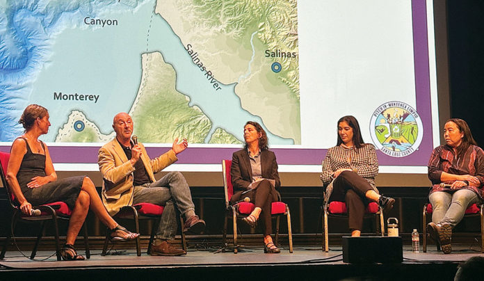 An ocean view, pollution included Panel of five speakers discussing ocean pollution at the Rio Theatre in Santa Cruz, seated before a map of Monterey Bay and the Salinas River.
