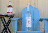 Tasting Sensation Bottles of Corralitos Apple Brandy and Corralitos Vodka displayed on a rustic blue chair and small table outdoors.