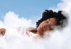 Playbook for Sleep Woman peacefully sleeping on soft white clouds beneath a clear blue sky.