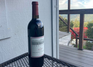 Smooth Blend A bottle of Silver Mountain Vineyards Alloy wine on an outdoor table overlooking a mountain view.
