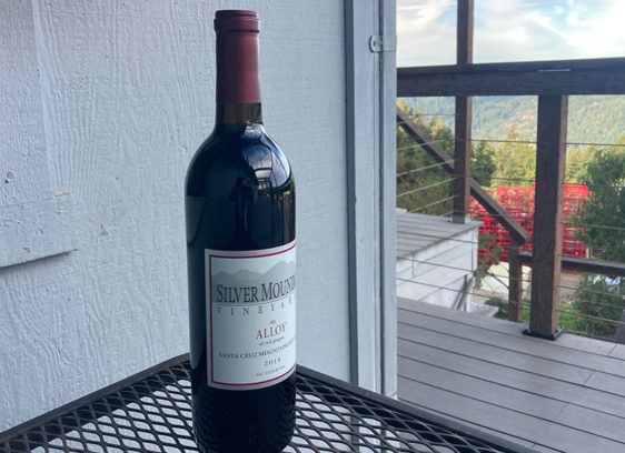 Smooth Blend A bottle of Silver Mountain Vineyards Alloy wine on an outdoor table overlooking a mountain view.