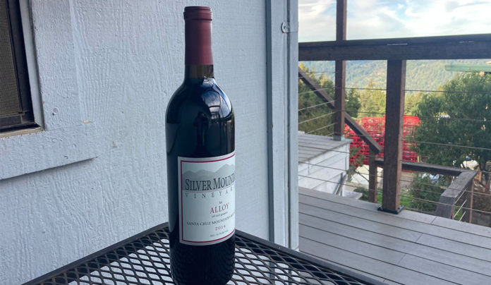 Smooth Blend A bottle of Silver Mountain Vineyards Alloy wine on an outdoor table overlooking a mountain view.