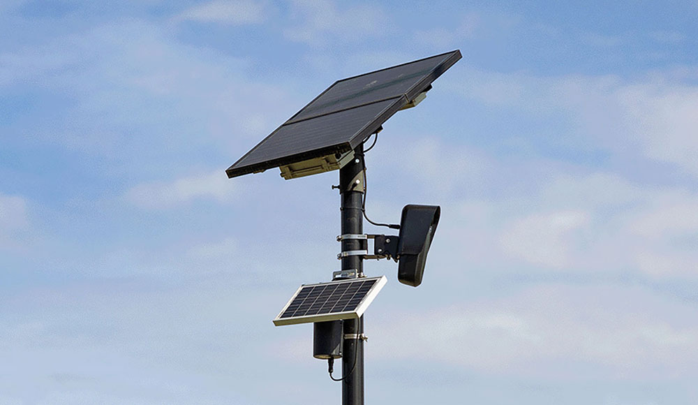 Solar-powered automated license plate reader mounted on a pole against a blue sky.