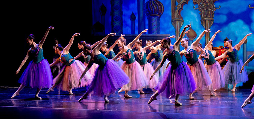 Ballet dancers perform the Waltz of the Flowers in vibrant purple and pink costumes.