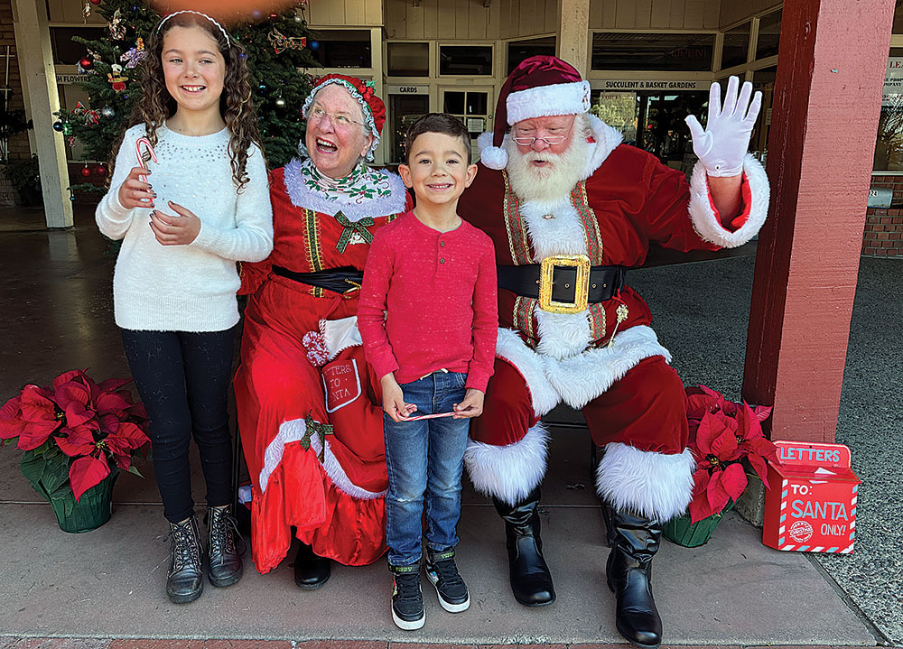 Two children pose with Santa and Mrs. Claus during a holiday event in Santa Cruz.