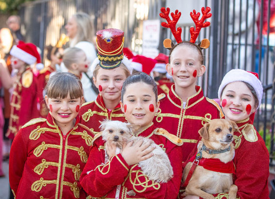 Solstice Groove Children dressed in festive toy-soldier costumes pose with two small dogs during a Santa Cruz holiday celebration.