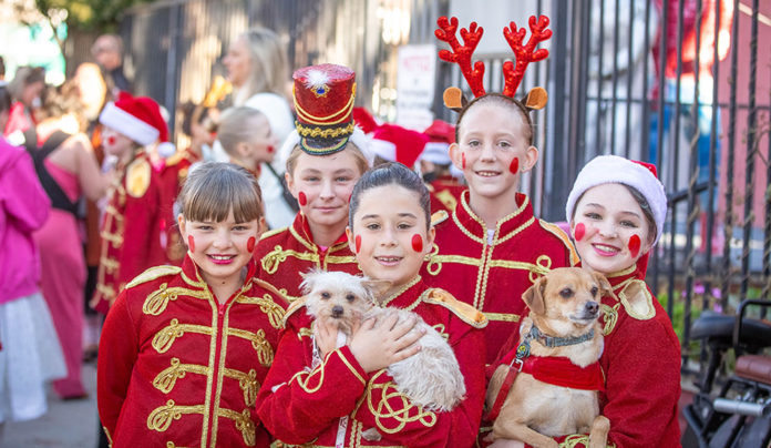 Solstice Groove Children dressed in festive toy-soldier costumes pose with two small dogs during a Santa Cruz holiday celebration.
