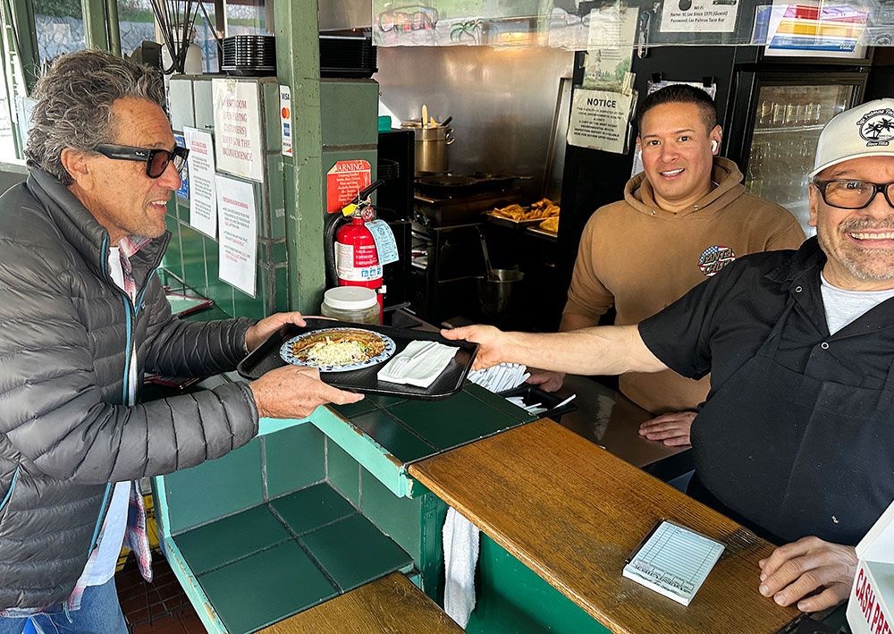 Customer receiving a plate of food at the counter from staff at Las Palmas Taco Bar in Santa Cruz.