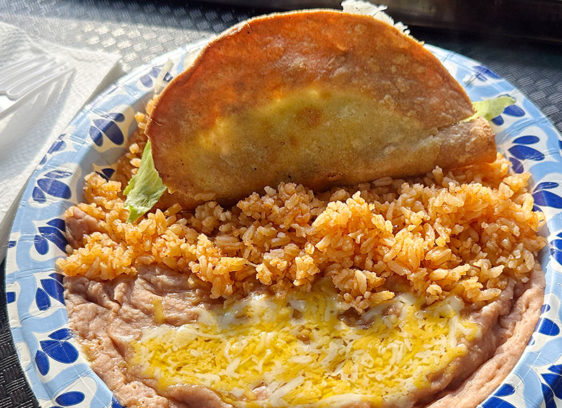 Taco Tradition Shredded beef crispy taco served with Mexican rice and refried beans topped with melted cheese at Las Palmas Taco Bar.
