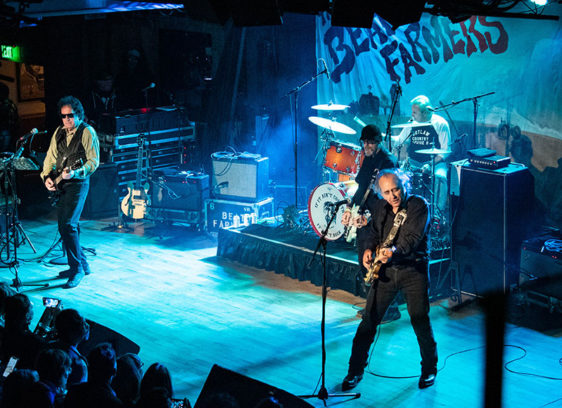Plowing Ahead The Beat Farmers performing live on stage with guitars and drums before a crowd at Moe’s Alley.